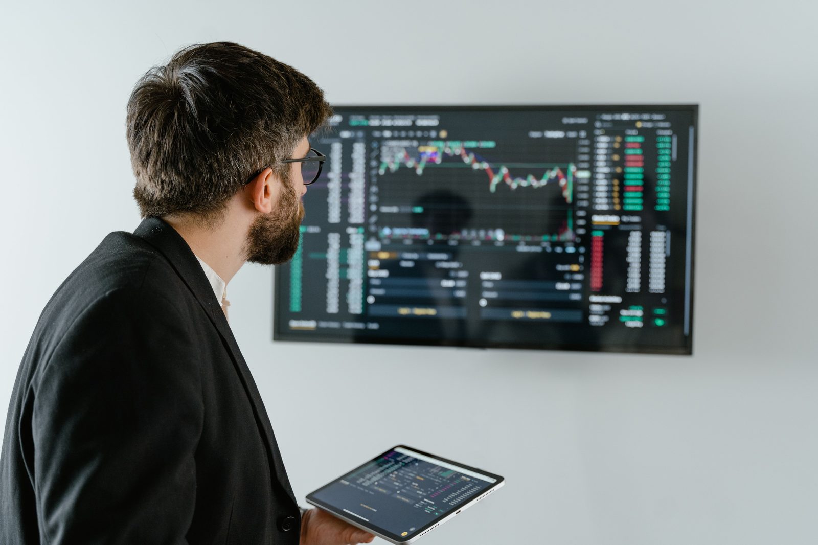 Person reviewing a dashboard on a wall-mounted screen and tablet